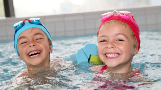 2 kleine meisjes samen in een zwembad met duikbril en zwembandjes
